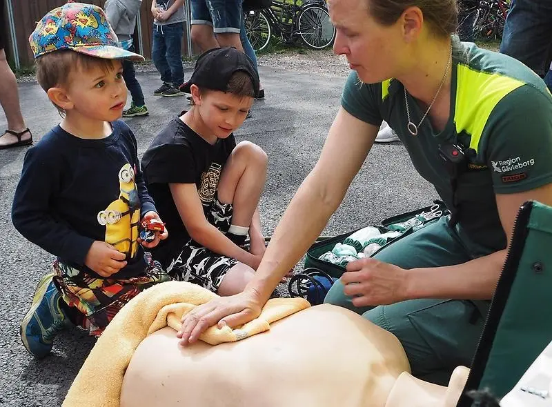 Ambulanspersonal visar barnen hjärt- och lungräddning
