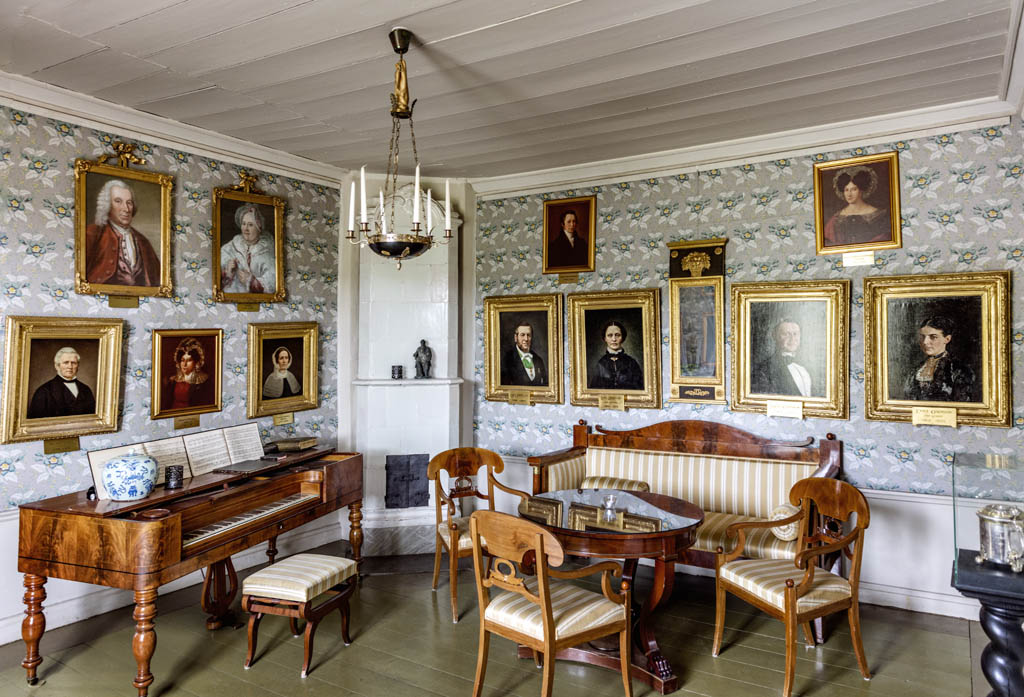 Ett rum i 1800-talsstil med sittgrupp och tavlor.