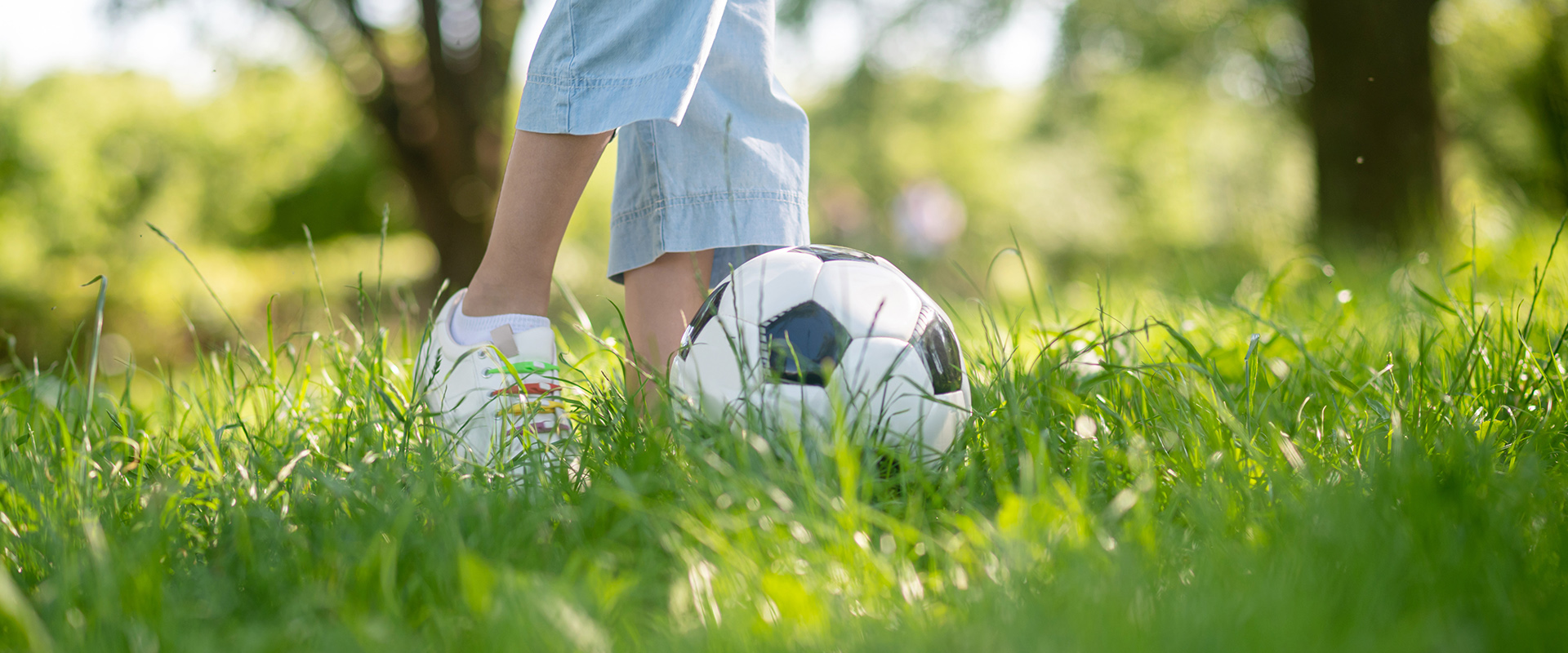 Ett par fötter sparkar en fotboll på gräs.
