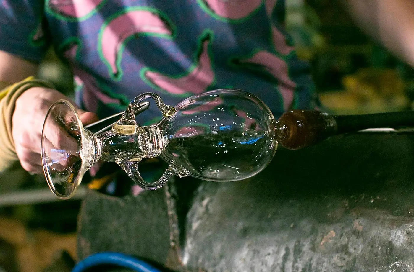 Glasblåsaren formar detaljer i en skir vas. 