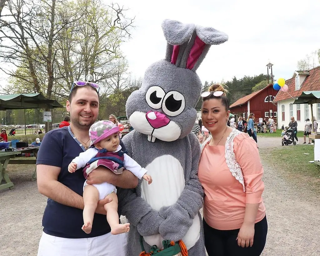 En stor grå kaninmaskot poserar med en barnfamilj.