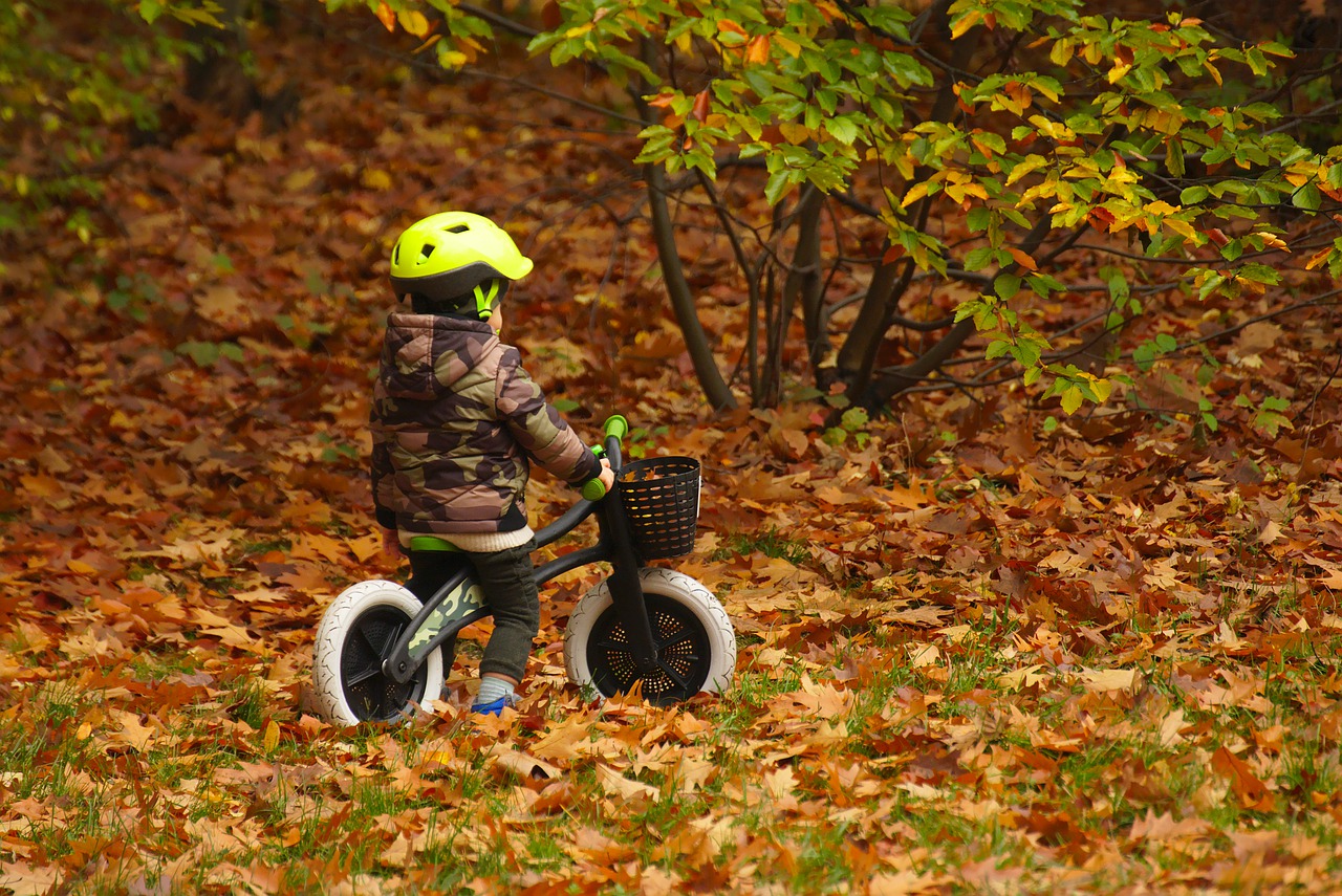 Ett litet barn cyklar bland höstlöv