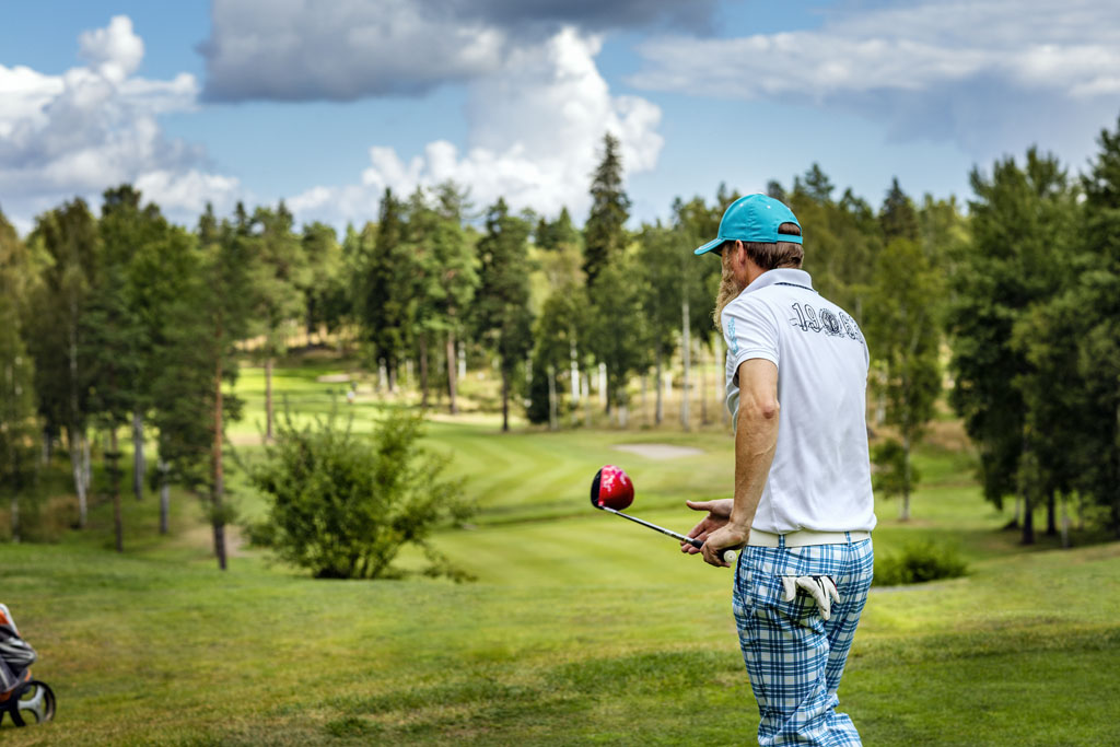 En golfare ser ut över en trädkantad golfbana. 