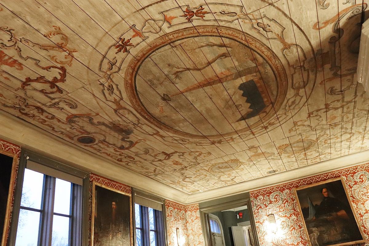 Ett 1700-talsrum med målat tak med ornament runt en mittmedaljong.
