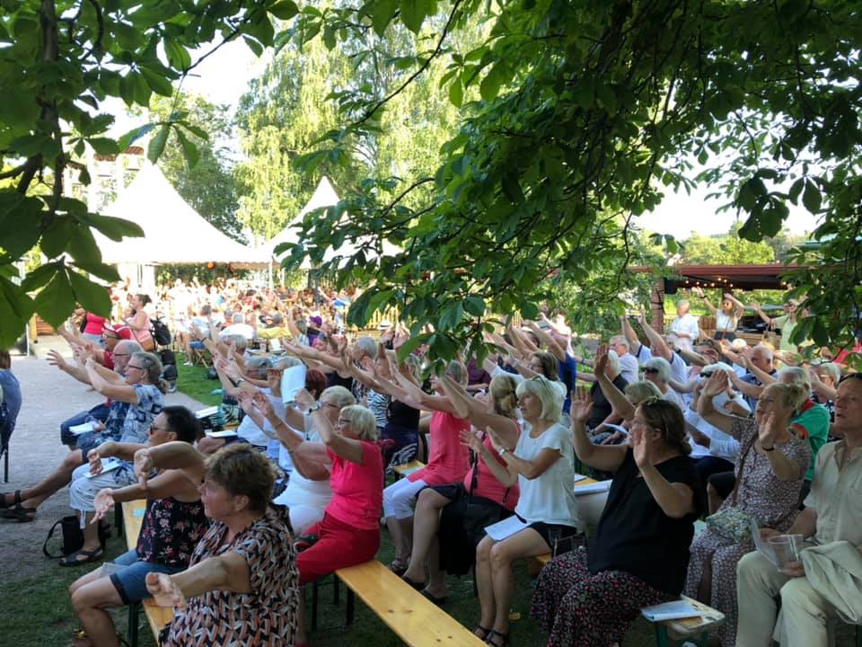 Människor som deltar i allsång och sträcker upp händerna i luften medan dom sjunger