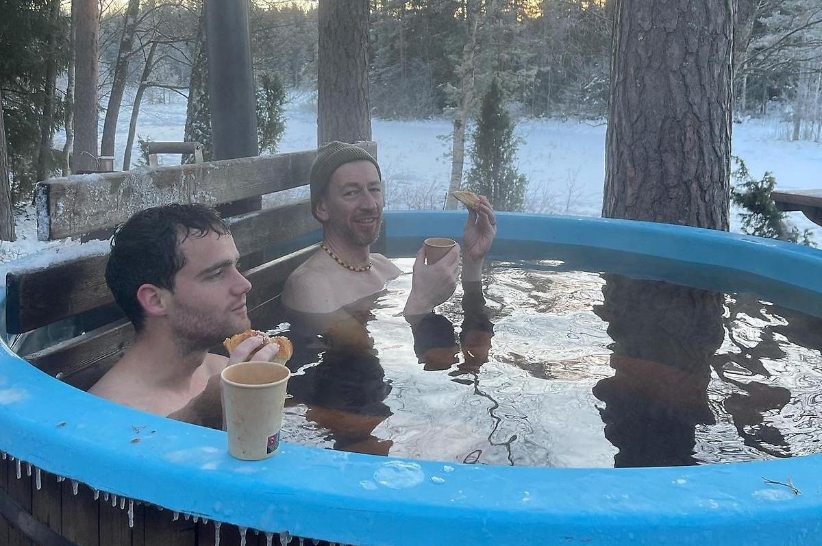 Två killar fikar och badar i tunna en vinterdag