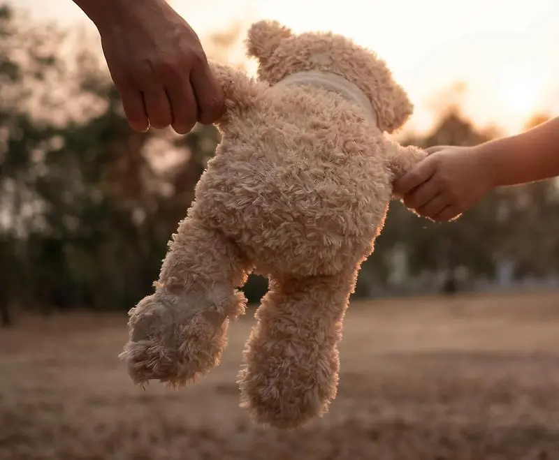 En vuxen och ett barn som håller en teddybjörn i vardera tass.